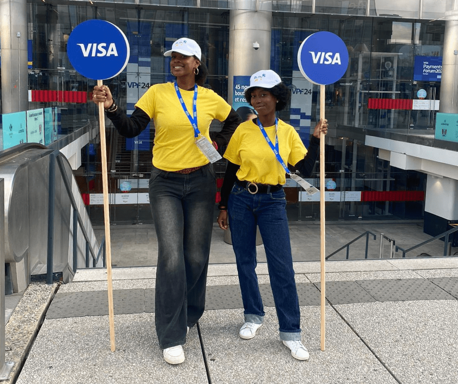 two women holding signs with the visa logo on them